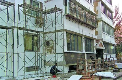 济南市某小区“暖房子”工程现场工人正在为楼体外墙贴保温板。