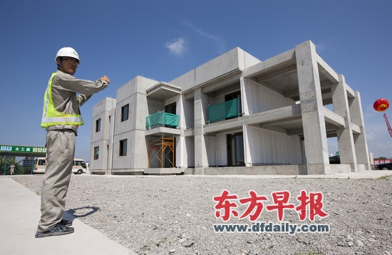 7月30日,上海浦东城建集团住宅产业化基地,“上海预制装配式建筑1号实验楼”装配现场,一位工人正在为即将落成的建筑留影。
